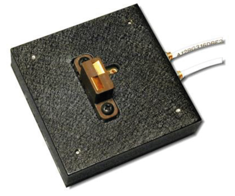 Square black textured panel with a copper-colored latch lock and two white wires protruding from the side.